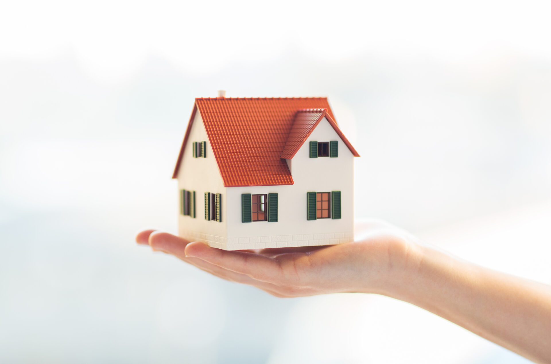 close up of hands holding house or home model architecture, building, construction, real estate and property concept - close up of hands holding house or home model